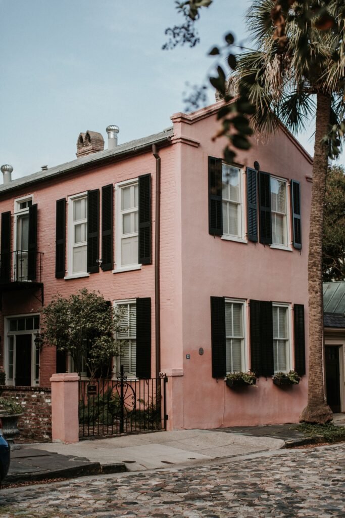 A picturesque pink house with black shutters and a palm tree, perfect for urban architectural themes.