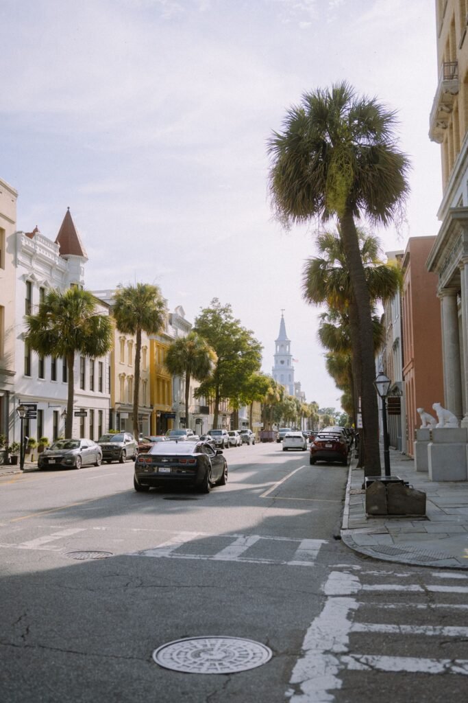 Summer day in Charleston, showcasing historic architecture and palm-lined streets with parked cars.